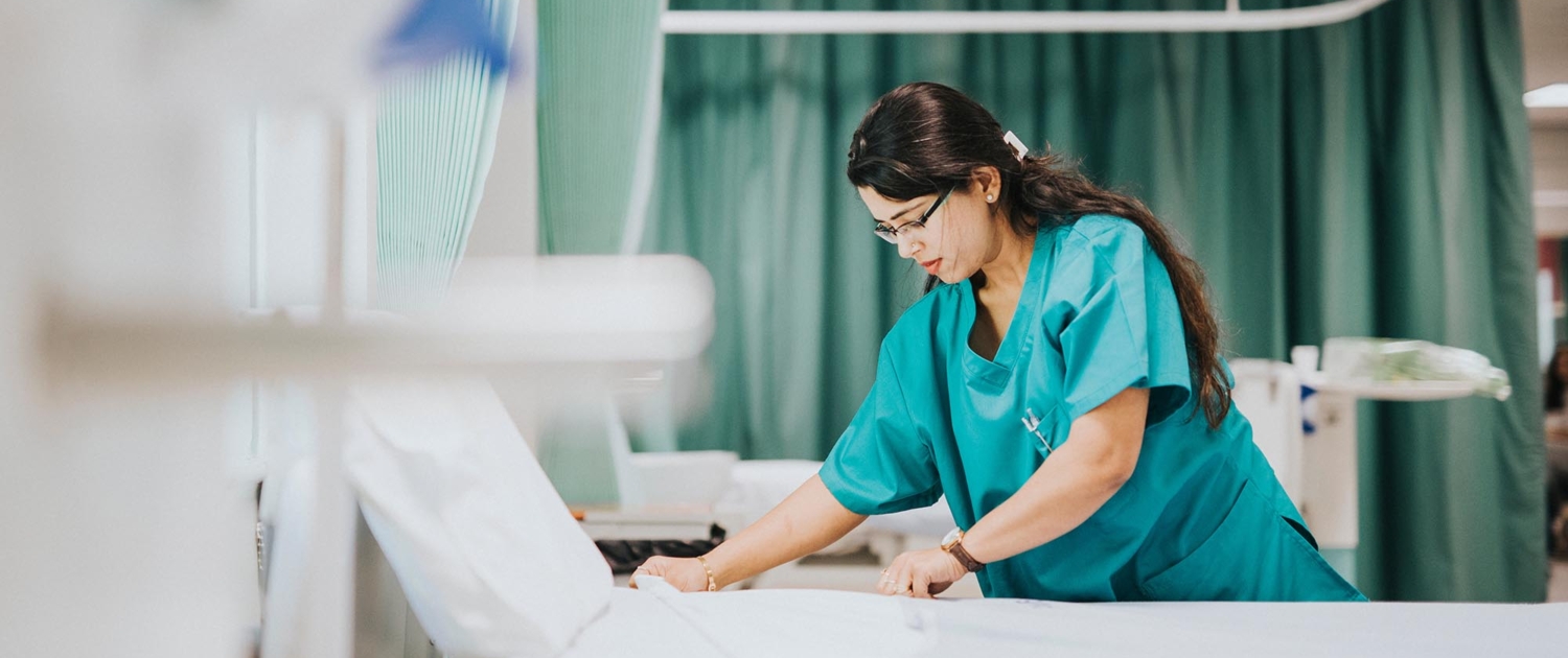 Healthcare worker making bed inside hospital