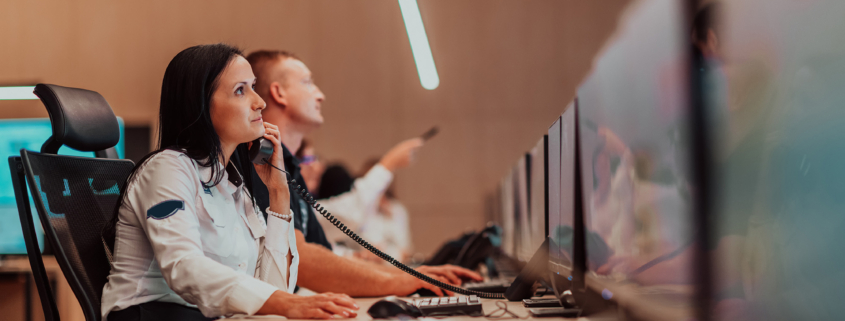 Female security guard operator talking on the phone while working at workstation