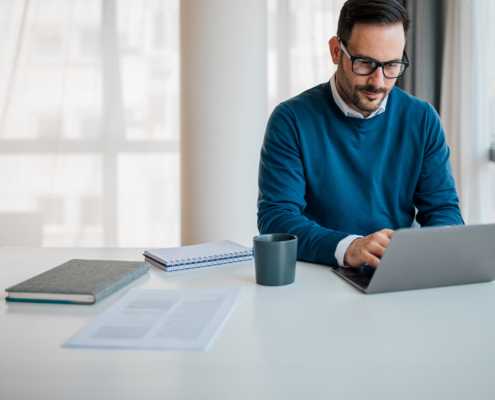 Front view of young professional doing financial work on computer, small business