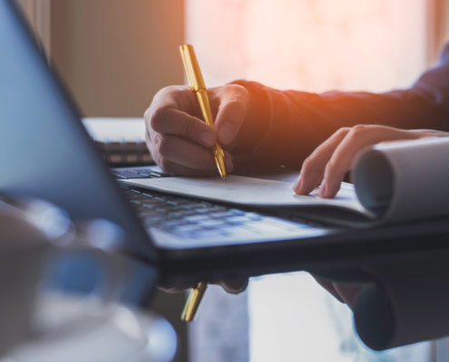 Business woman hand write and sign cheque book with laptop