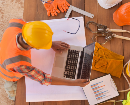 Top view of architectural engineer useing laptop on his blueprints