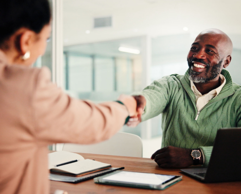 Two people shaking hands over a desk